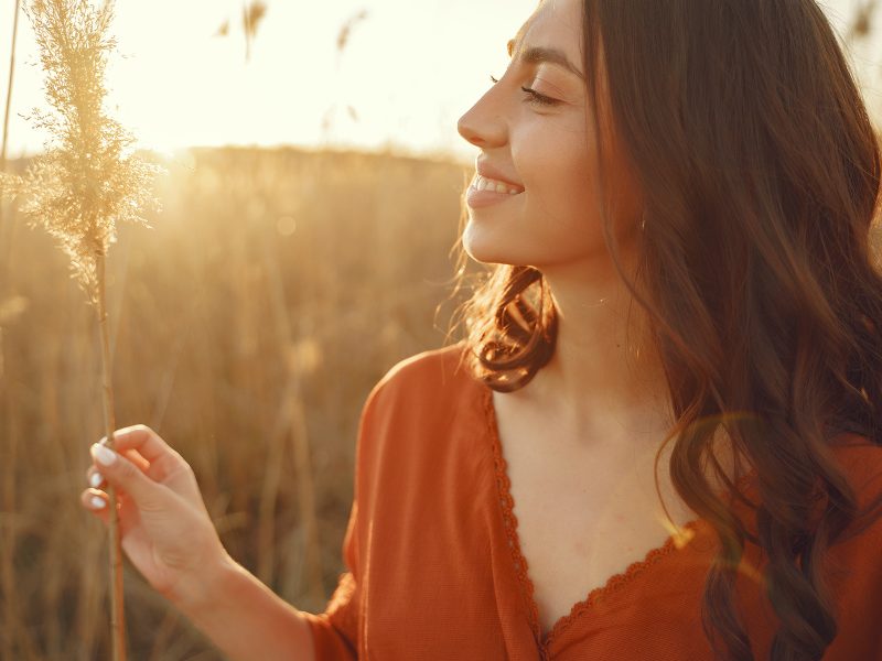 Woman in a summer field. Brunette in a yellow skirt. Girl on a sunset background.