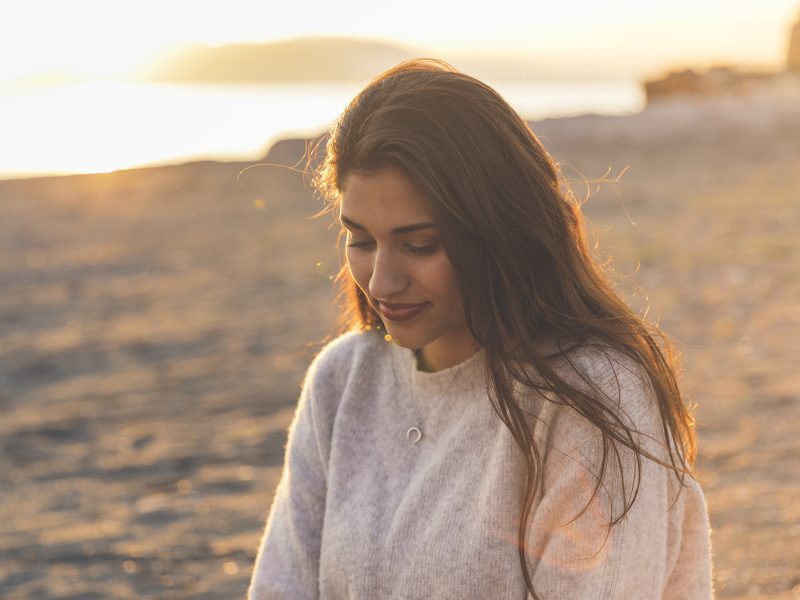 young-woman-sweater-sitting-sandy-sea-shore
